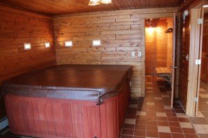 The large hot tub that comes with the house and door way leading to the sauna
