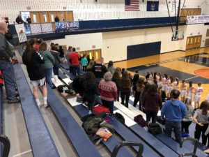 The Redettes stand for the National Anthem.