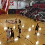 A Redmen takes on a Trojan as he makes his way down the court.