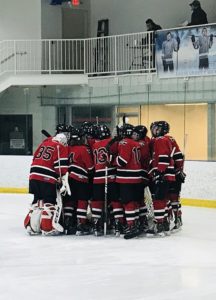 The Redmen huddle up before their bout against the Salem High School Rocks.