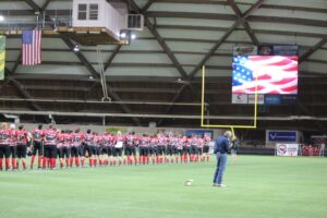 A wide-shot of the singing of the National Anthem