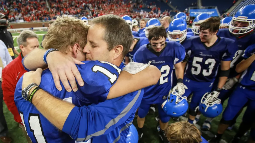 Coach Olson hugs his son Isaac after winning the 2015 state championship. Photo credit: Detroit Free Press.